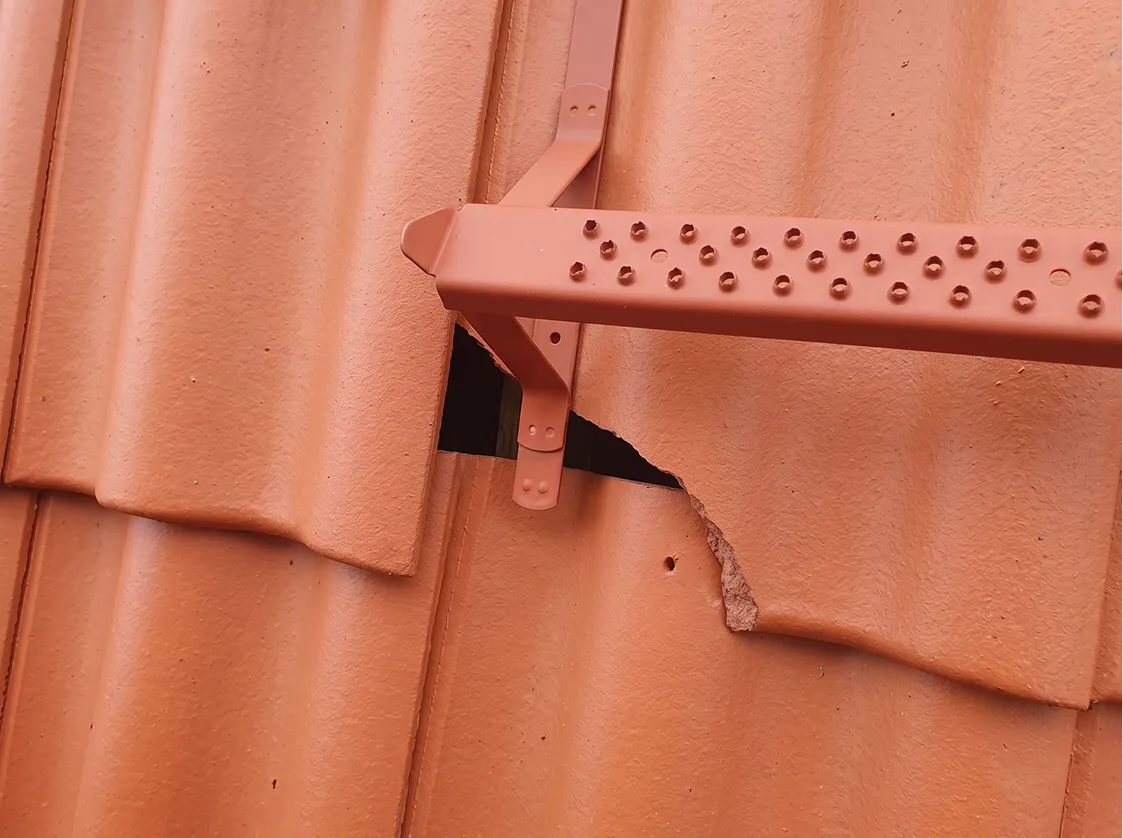 Närbild på skadad takpanna med flagnande ytskikt efter högtryckstvätt
