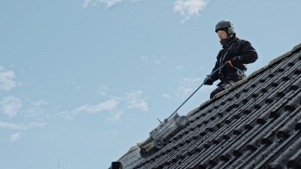 Taktekniker med fallskydd som tvättar tak